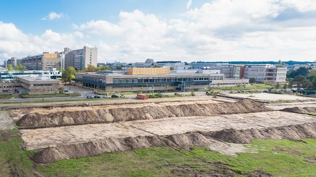 Blick auf das Baufeld am Stadtfelddamm mit aufgehäuften großen Sandbergen und dem Campus im Hintergrund